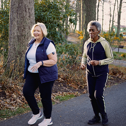 Dwie spacerujące kobiety korzystające z urządzeń CGM Eversense.
